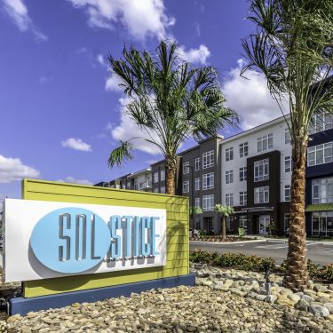 Solstice Apartments building exterior with sign and surrounding palm trees