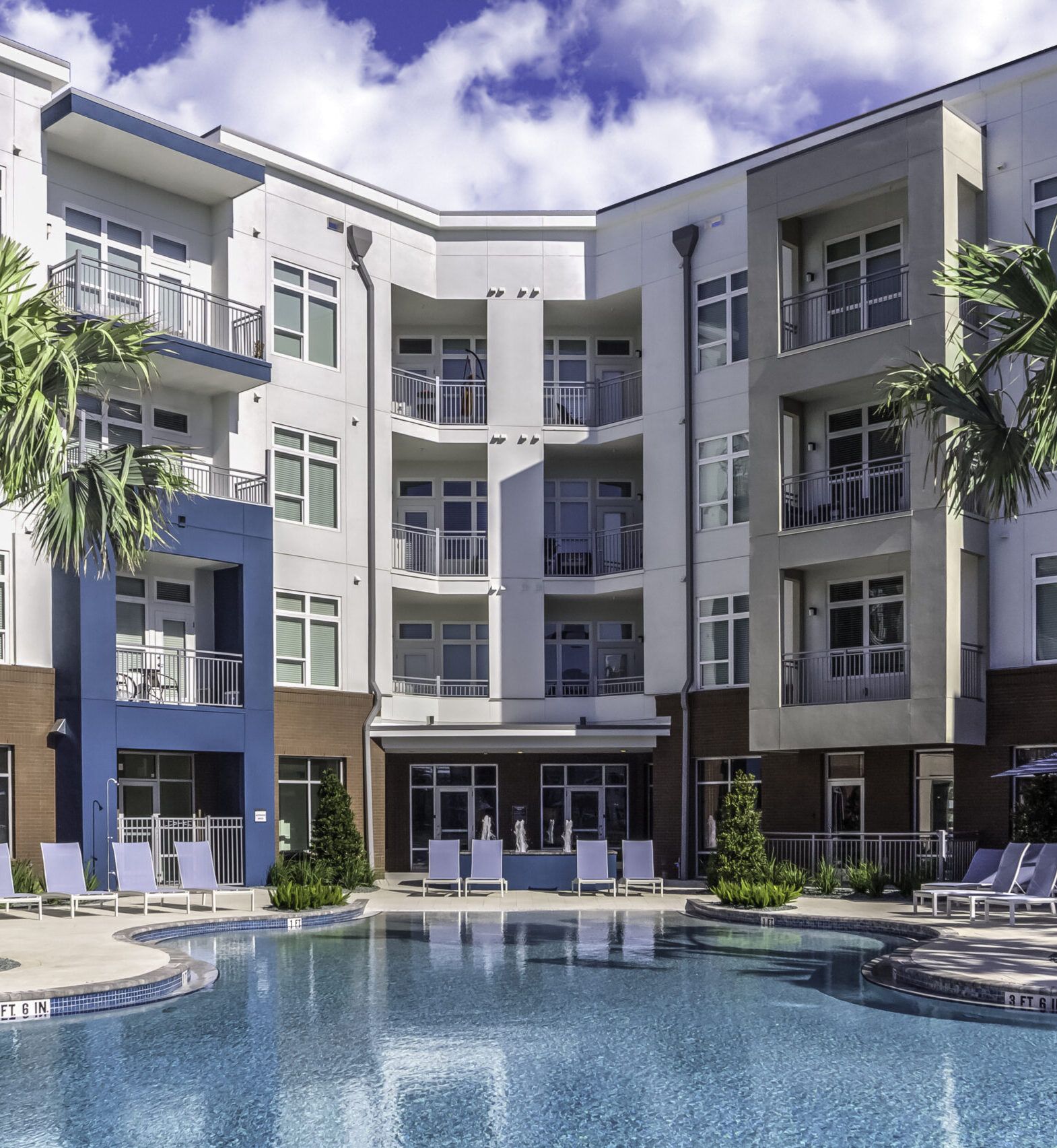Solstice Apartments relaxing pool at sunset with ample lounge seating and palm tree landscaping.