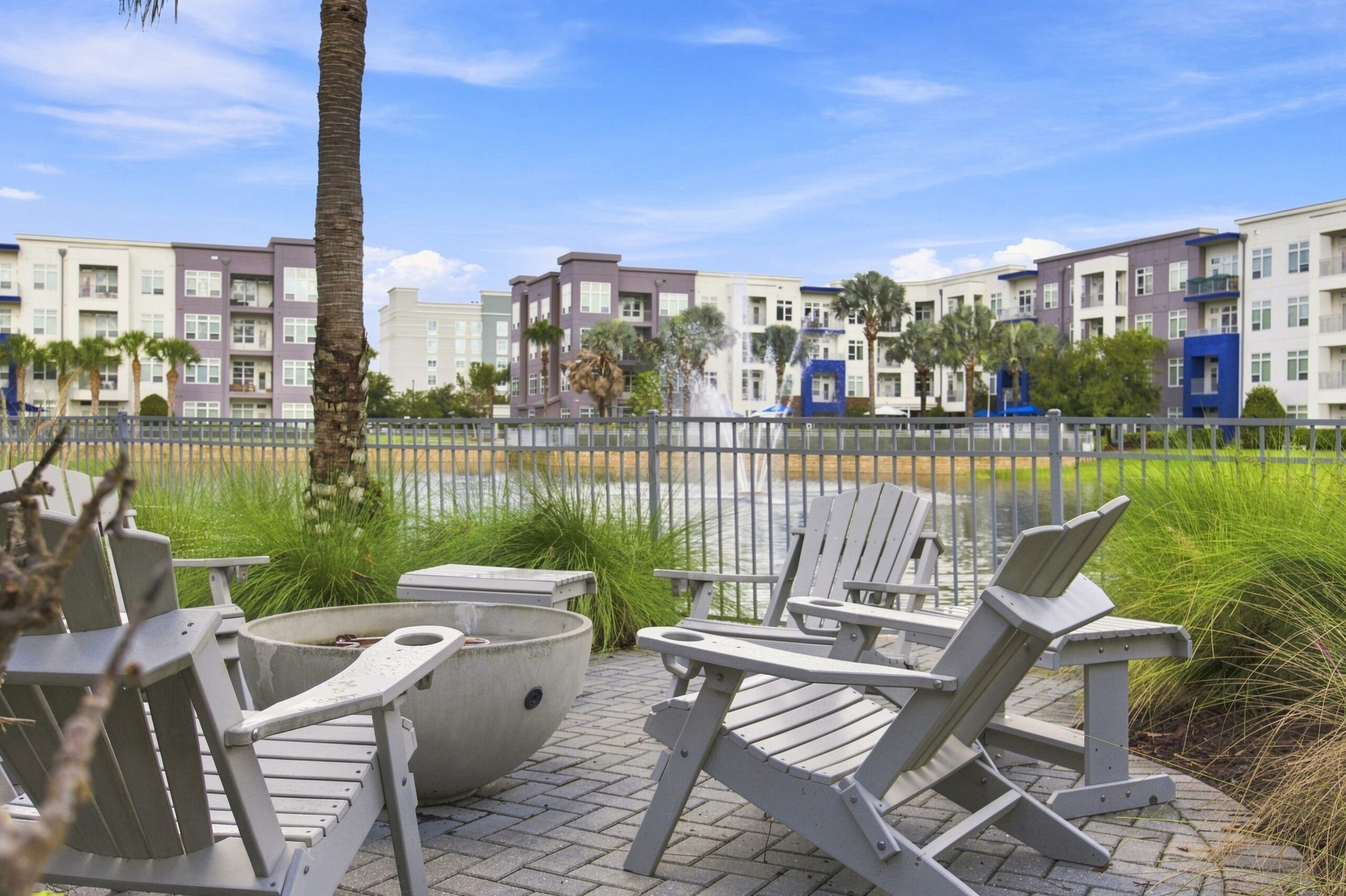 Solstice Apartments outdoor lounge area with Adirondack chairs circled around a fire pit with a lakeside view.