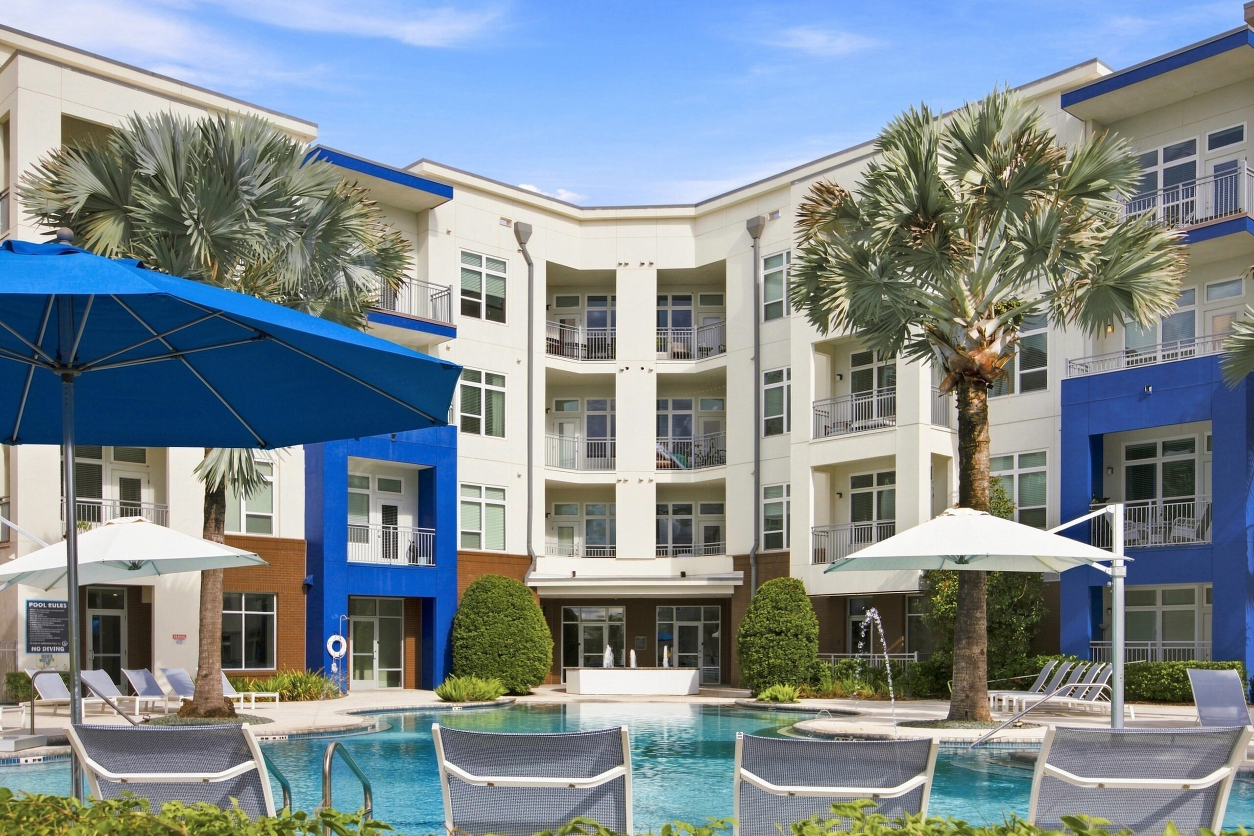 Solstice Apartments relaxing pool at sunset with ample lounge seating and palm tree landscaping.