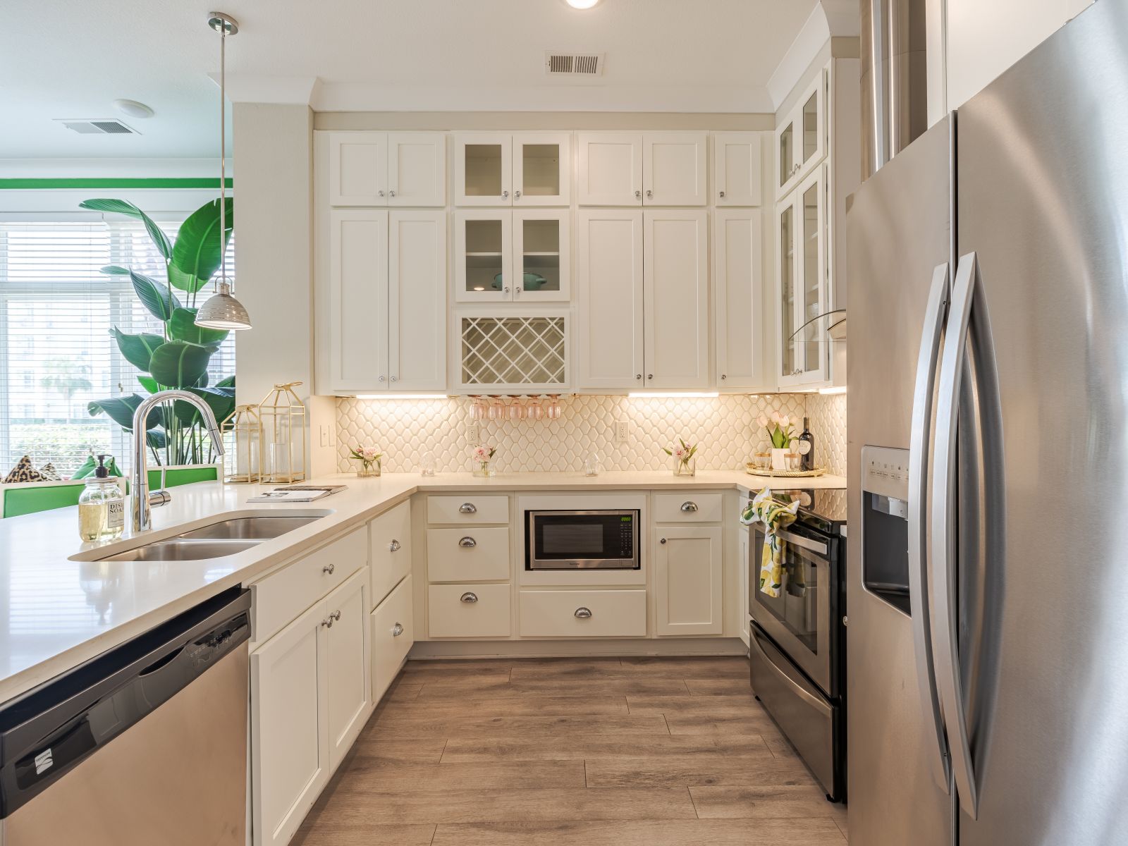 Contemporary kitchen in Solstice Apartments with white cabinetry, a central island, and stainless steel appliances, flowing into a brightly lit living area.