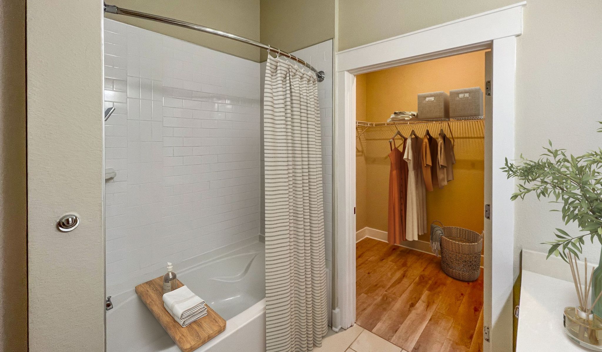 Elegant bathroom at Solstice Apartments equipped with large bathtub and shower, and a connected walk-in closet with organized storage.