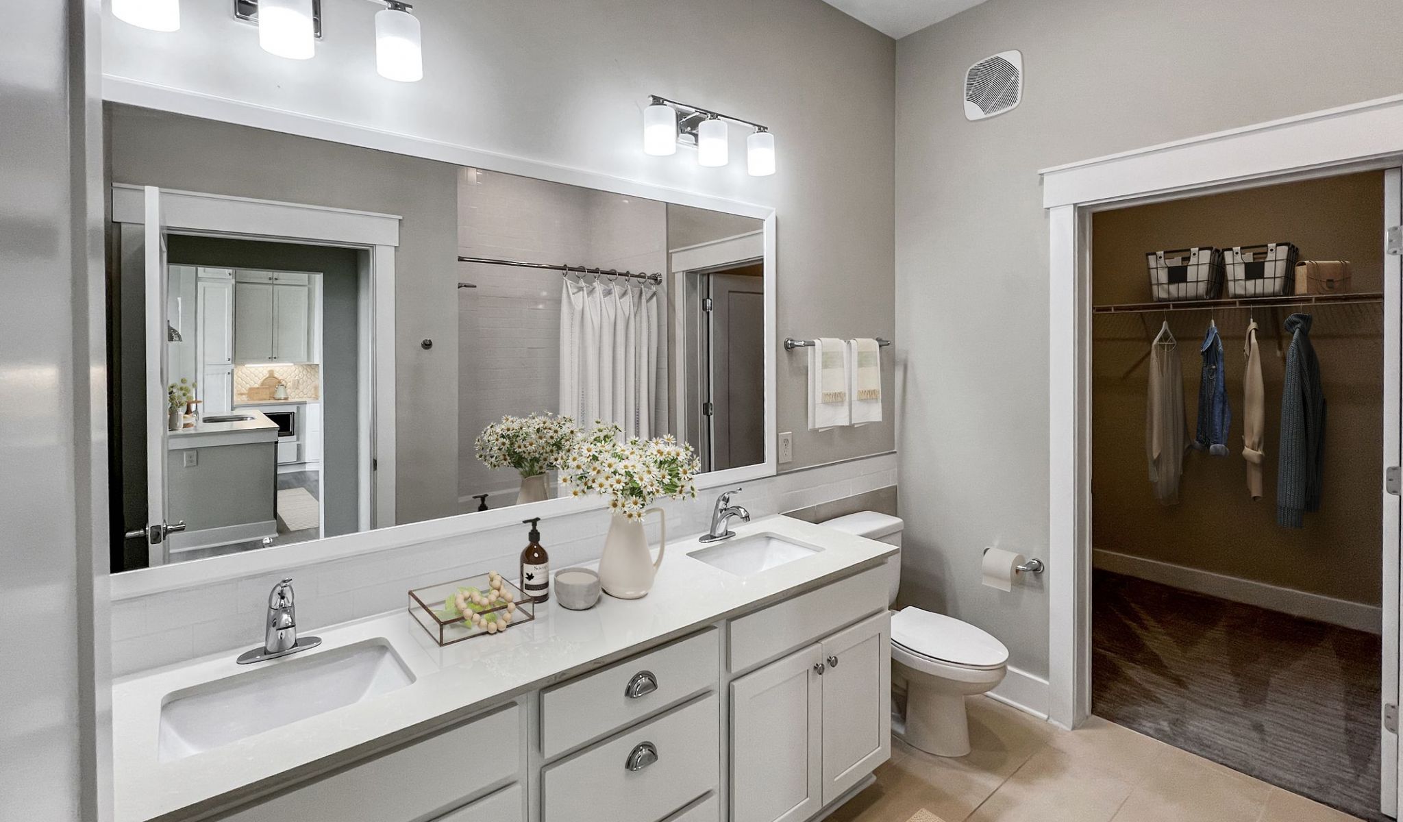 Elegant bathroom at Solstice Apartments equipped with dual sinks and a connected walk-in closet with organized storage.