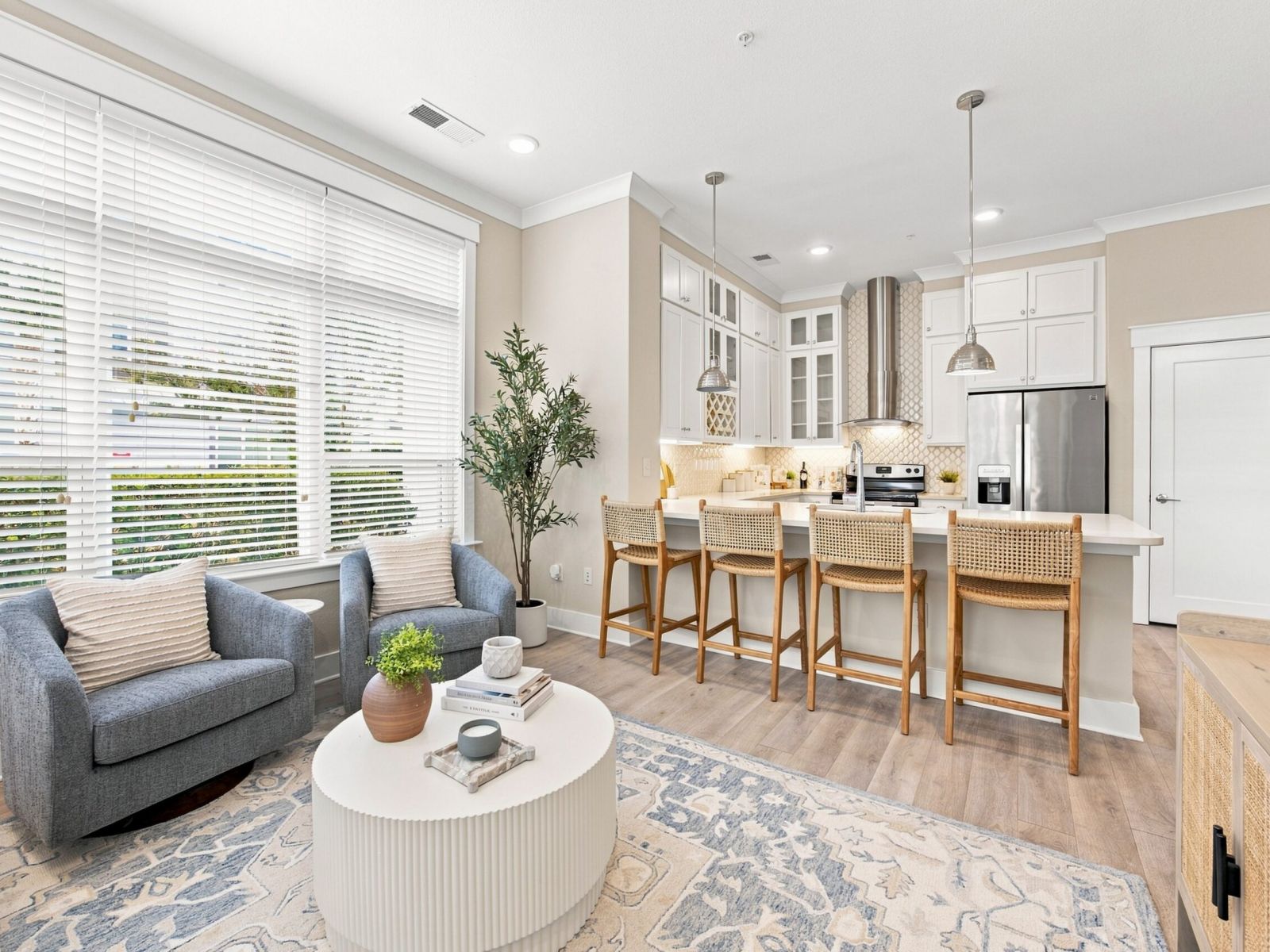 A spacious and modern living room at Solstice Apartments featuring a green sofa, wooden furniture, and decorative plants enhancing the cozy ambiance.